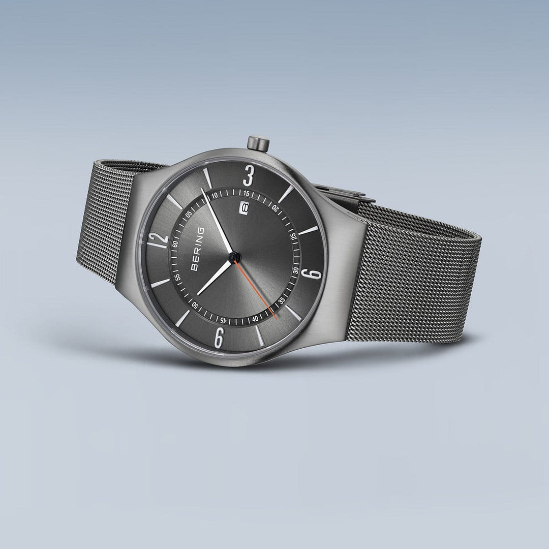 Grey men's watch with a titanium case and Milanese strap.