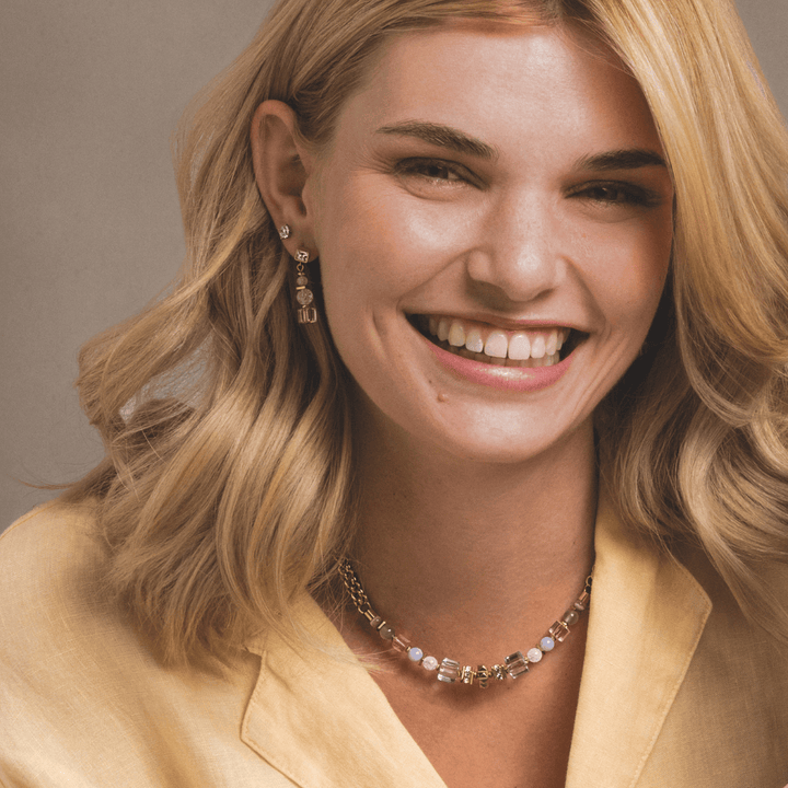 Model wearing Coeur de Lion Gold & Pastel coloured Nexus necklace, bracelet & earrings set - Carathea & Jools