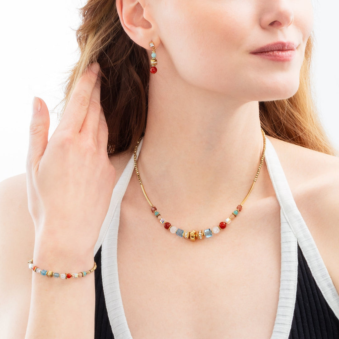 Model wearing Coeur de Lion gold and multicoloured necklace,bracelet and earrings set features round and cube beads - Carathea & Jools