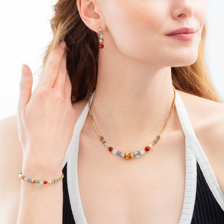 Model wearing Coeur de Lion gold and multicoloured necklace,bracelet and earrings set features round and cube beads - Carathea & Jools