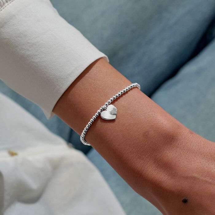 Silver heart charm bracelet on a stretchable beaded strand.