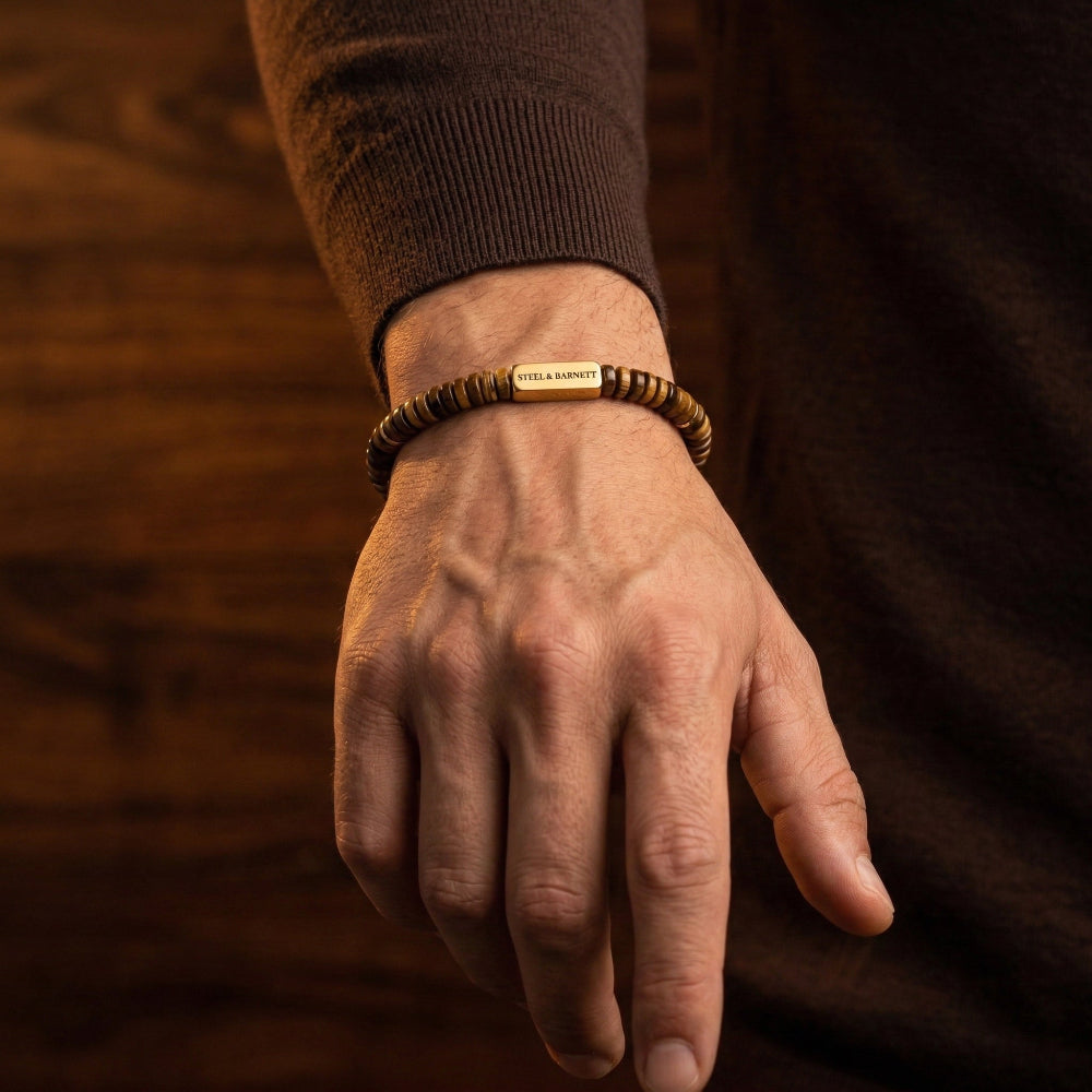 Men's Hand wearing a Tiger's Eye bracelet with a blurred background