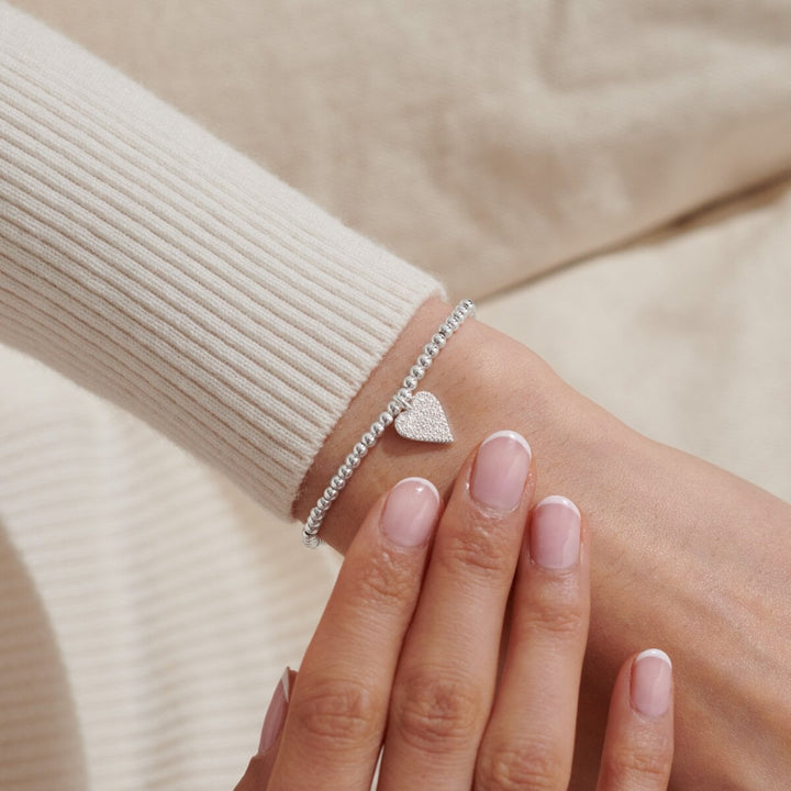 a silver-plated beaded bracelet with heart charm on white card 
