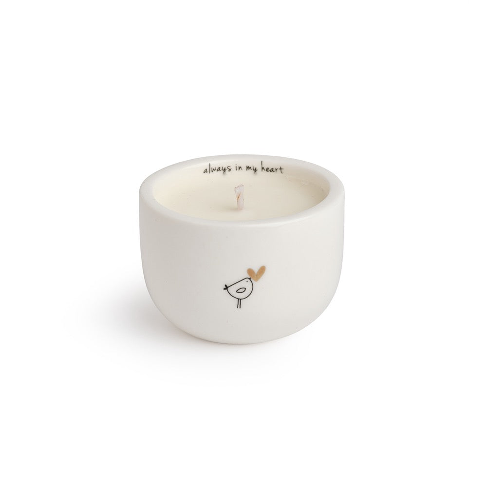 Belly Button Always in My Heart candle in a round cream ceramic pot with its message inside the rim and a bird outside.