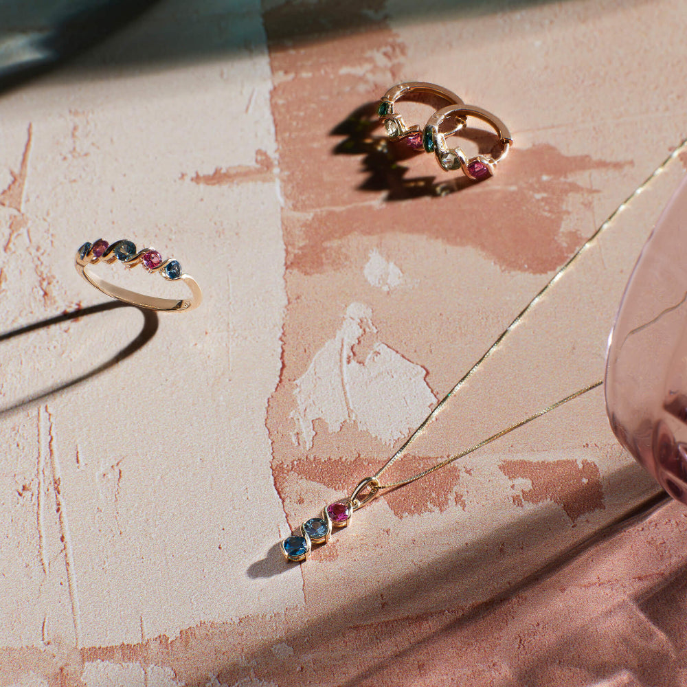 Gold rings with colorful gemstones on a textured surface