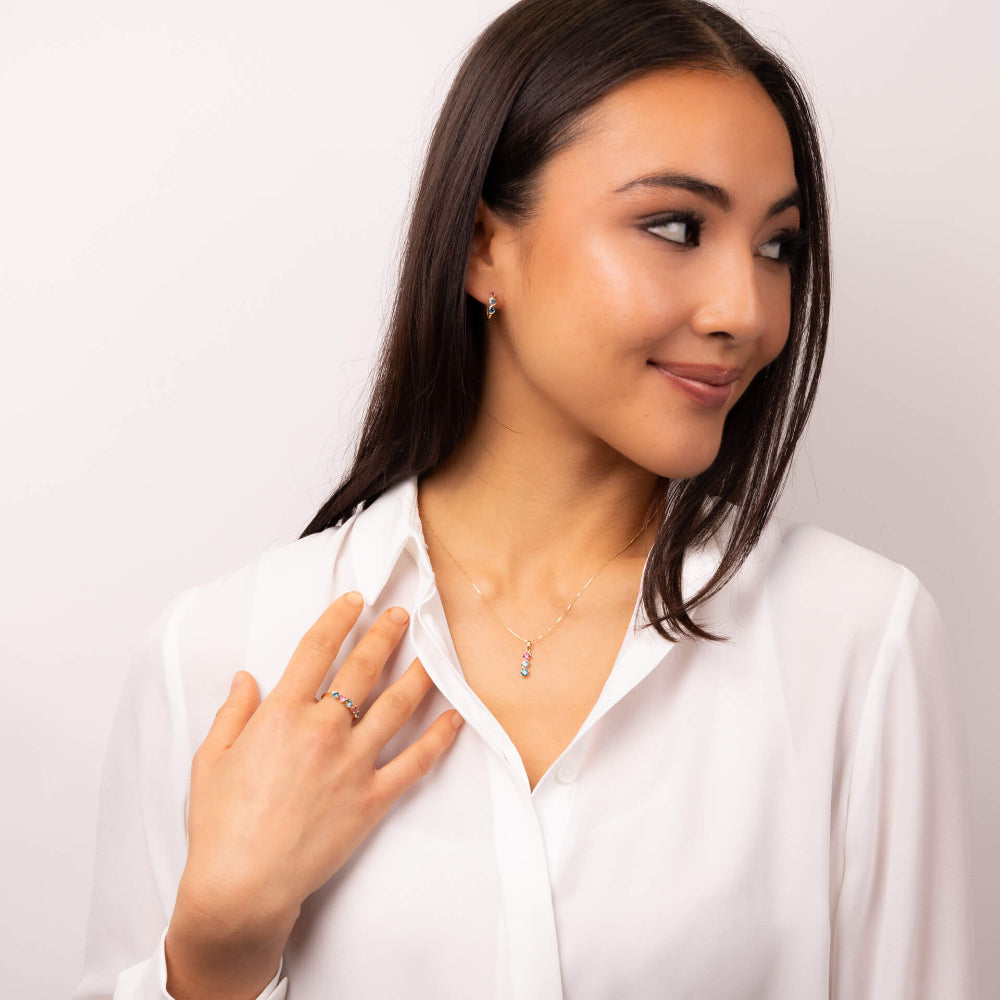 Woman wearing a necklace and ring on a plain background