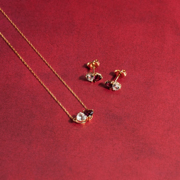 Gold necklace and earrings with gemstones on a red background