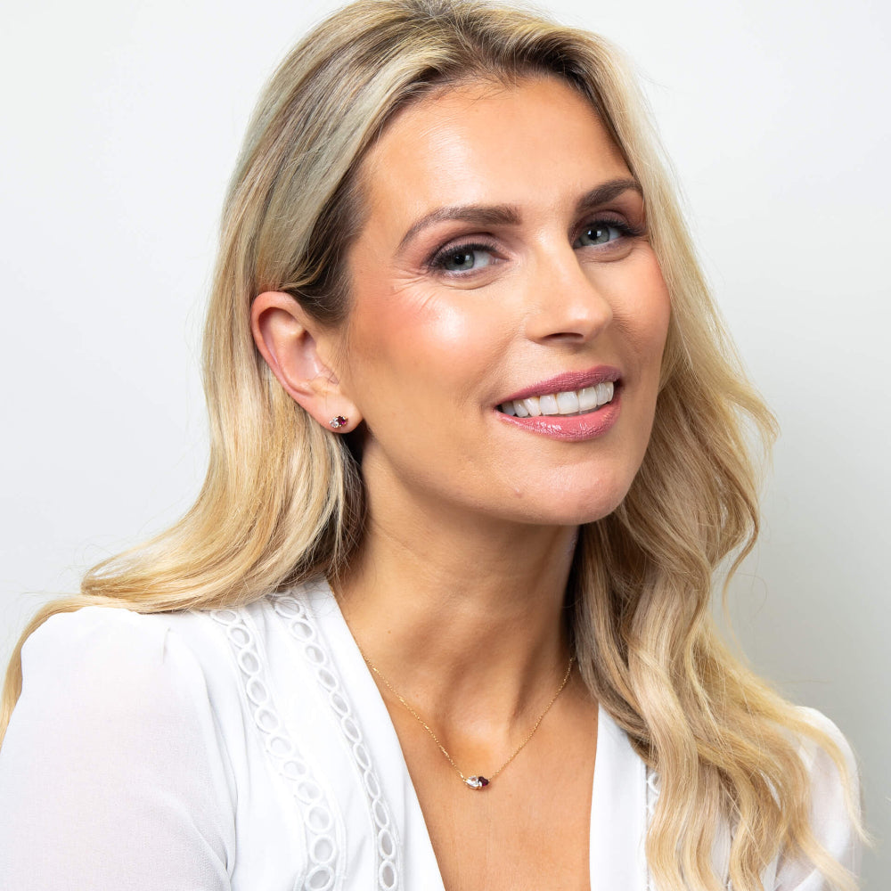 Woman with blonde hair and a white top against a plain background