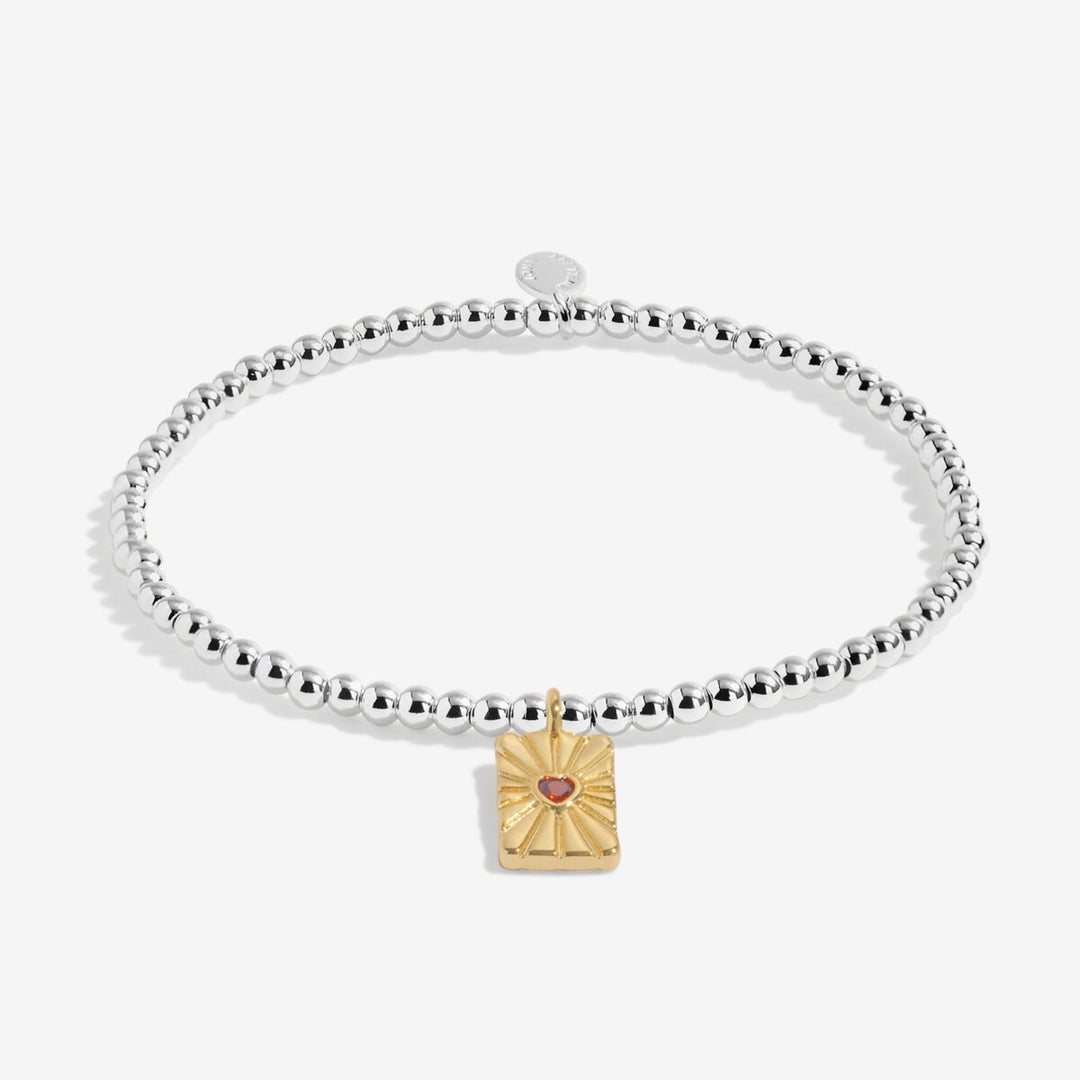 Silver and gold beaded bracelet with a heart charm and red crystal.