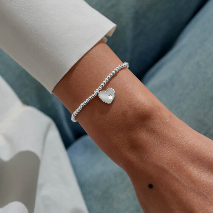 Silver and gold beaded bracelet with a heart charm and red crystal.