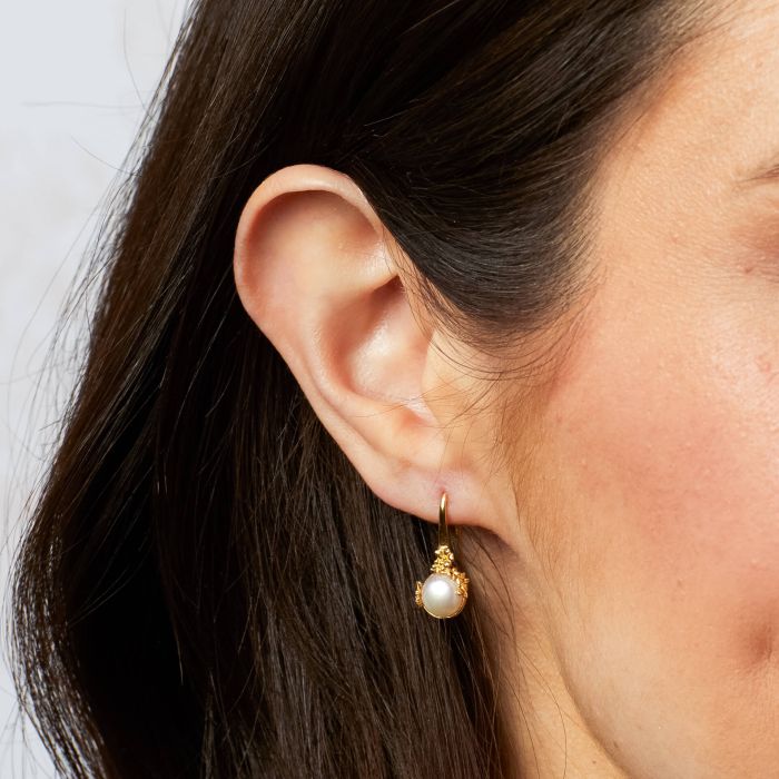 Pearl Tulip Earrings are gold-plated, recycled sterling silver earrings shaped like tulips, each holding a white freshwater pearl.