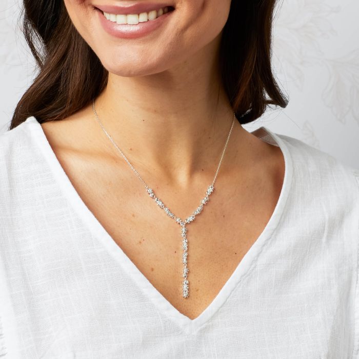 Silver lariat necklace with floral details.
