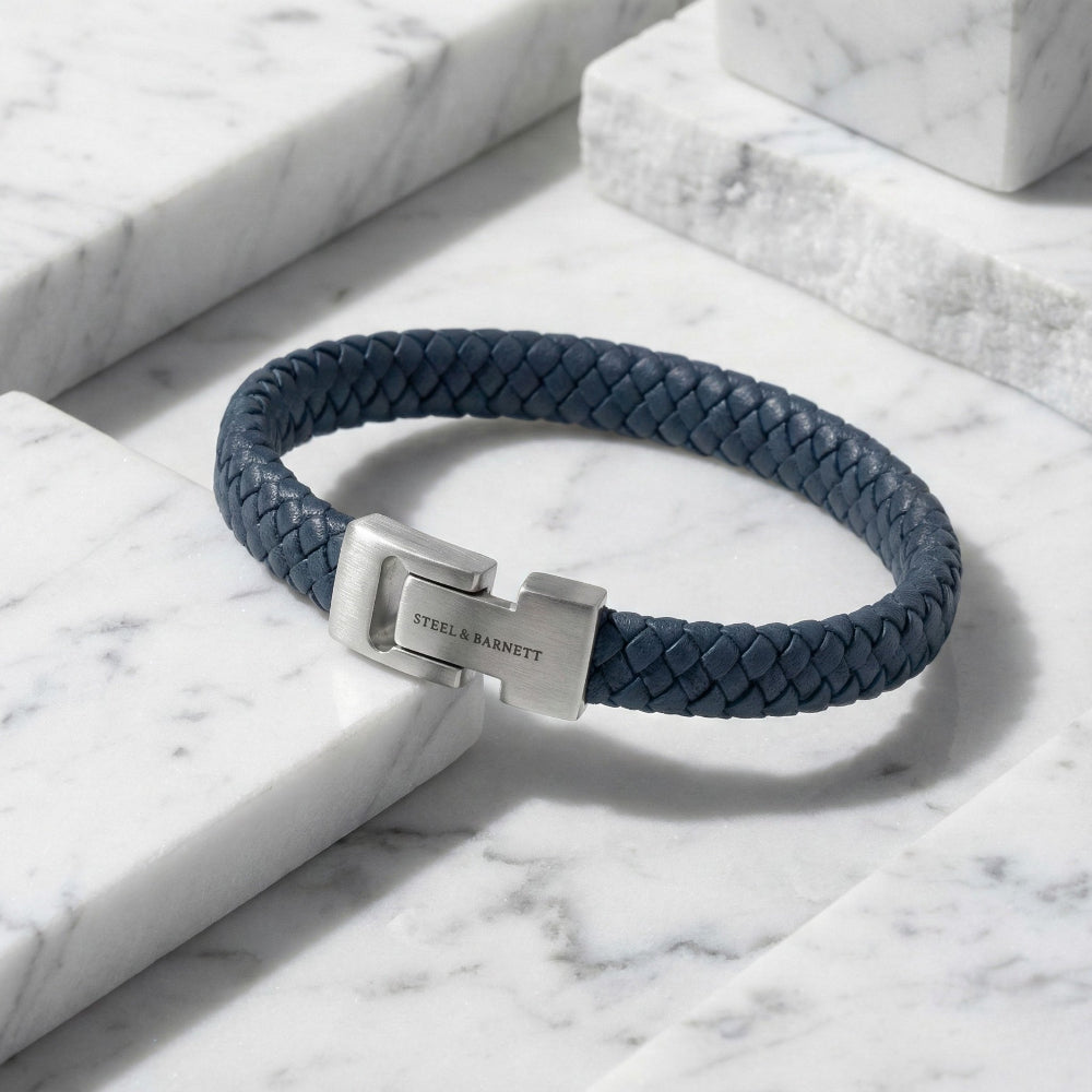 Navy braided bracelet with a silver clasp on a marble surface