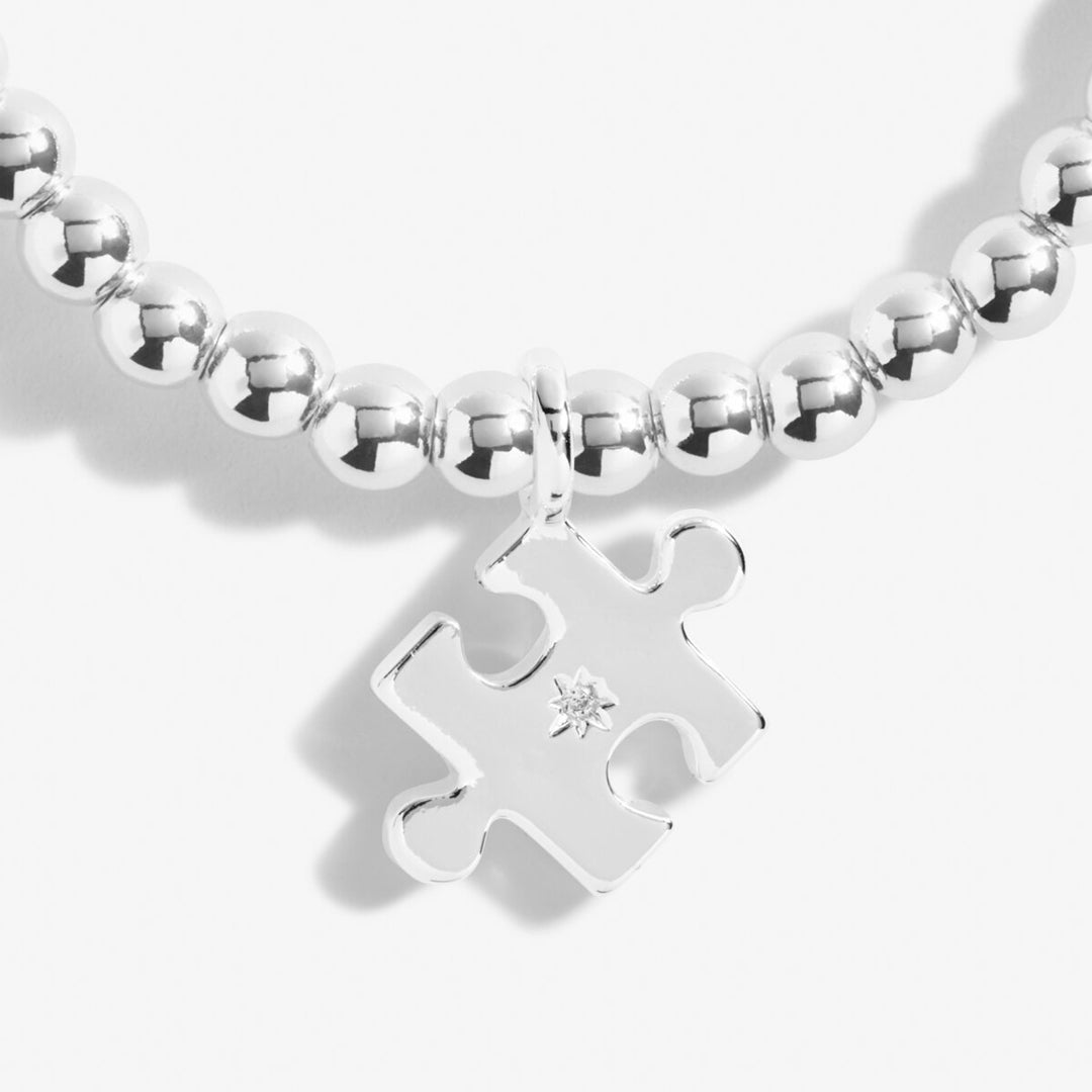 Silver bracelet with a puzzle piece charm on a white background