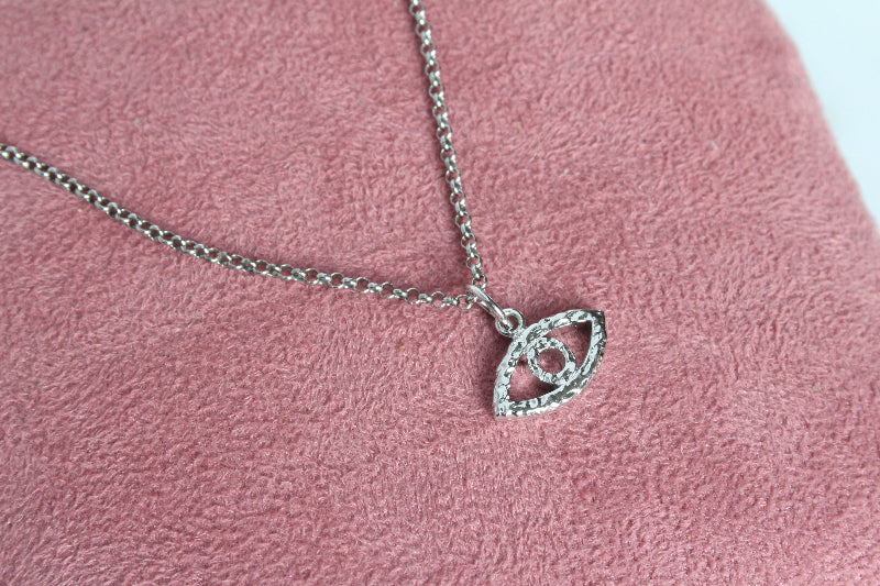 Silver evil eye pendant on pink cushion
