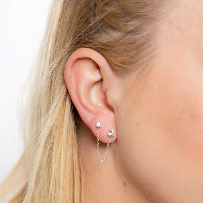Sterling silver stud earrings with a delicate chain.