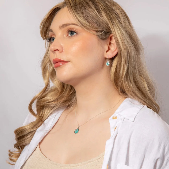 These are turquoise drop earrings with pendant have sterling silver settings and flower patterns, suitable as a December birthstone gift | Carathea & Jools