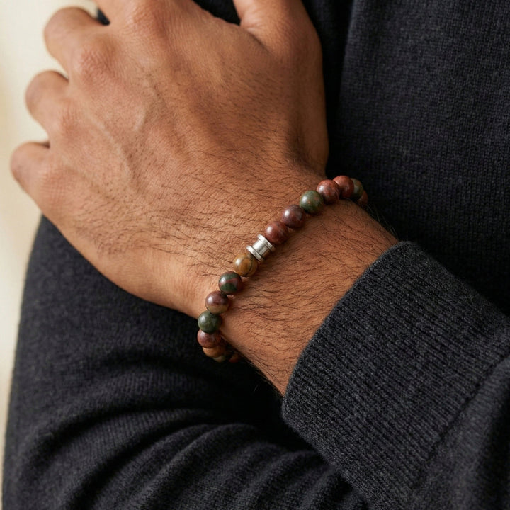 Hand wearing a beaded bracelet with a dark sweater sleeve.