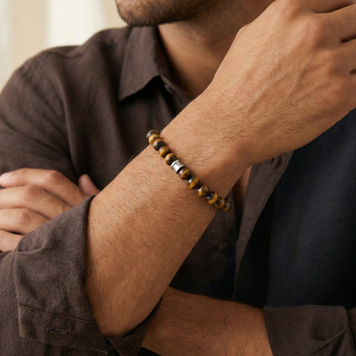 Man wearing a beaded bracelet on his wrist with a neutral background