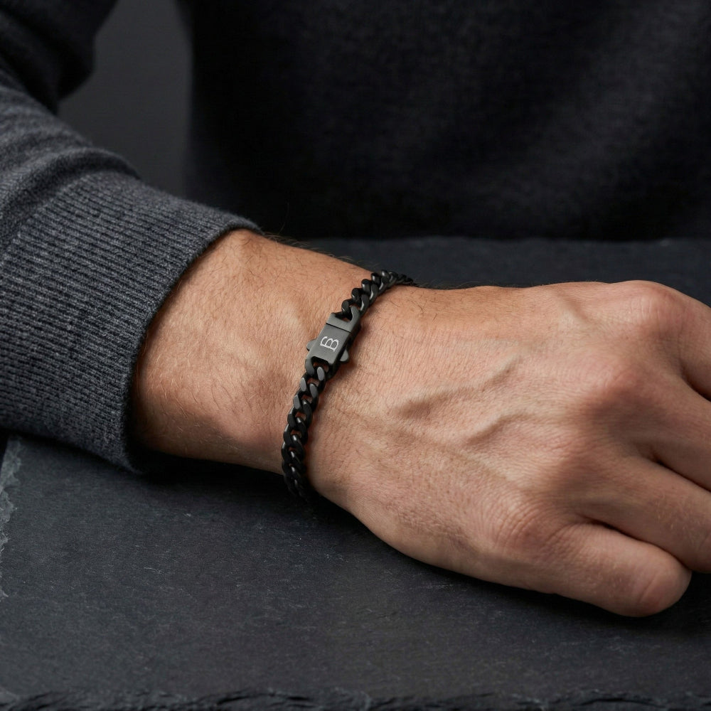 Close-up of a person's wrist wearing a black bracelet on a dark surface