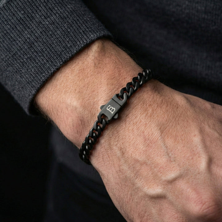 Black chain bracelet on a wrist with a dark background