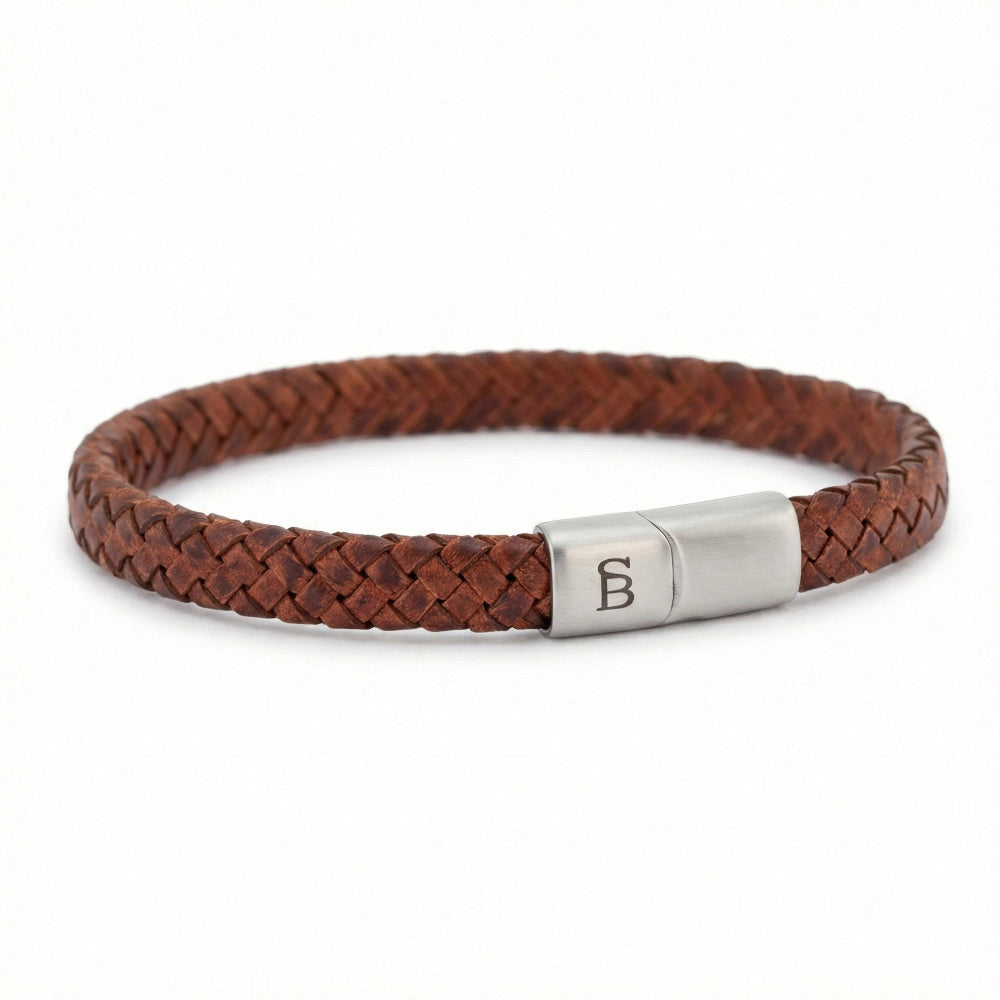 A brown braided leather bracelet with a silver-toned metal clasp engraved with the letter 'B', shown on a plain white background.
