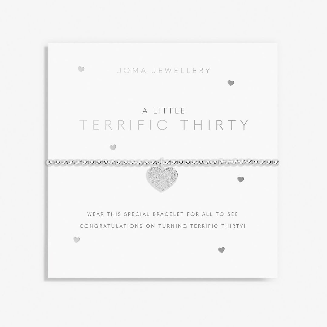 A silver beaded bracelet with a textured heart charm, presented on a white Joma Jewellery 'A Little Terrific Thirty' card.
