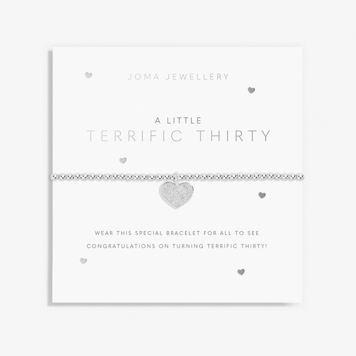 A silver beaded bracelet with a textured heart charm, presented on a white Joma Jewellery 'A Little Terrific Thirty' card.