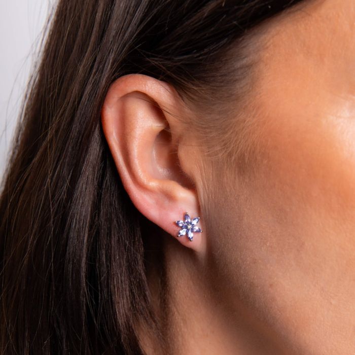 close up on model of white gold tanzanite flower stud earrings with diamond - Carathea jewellers